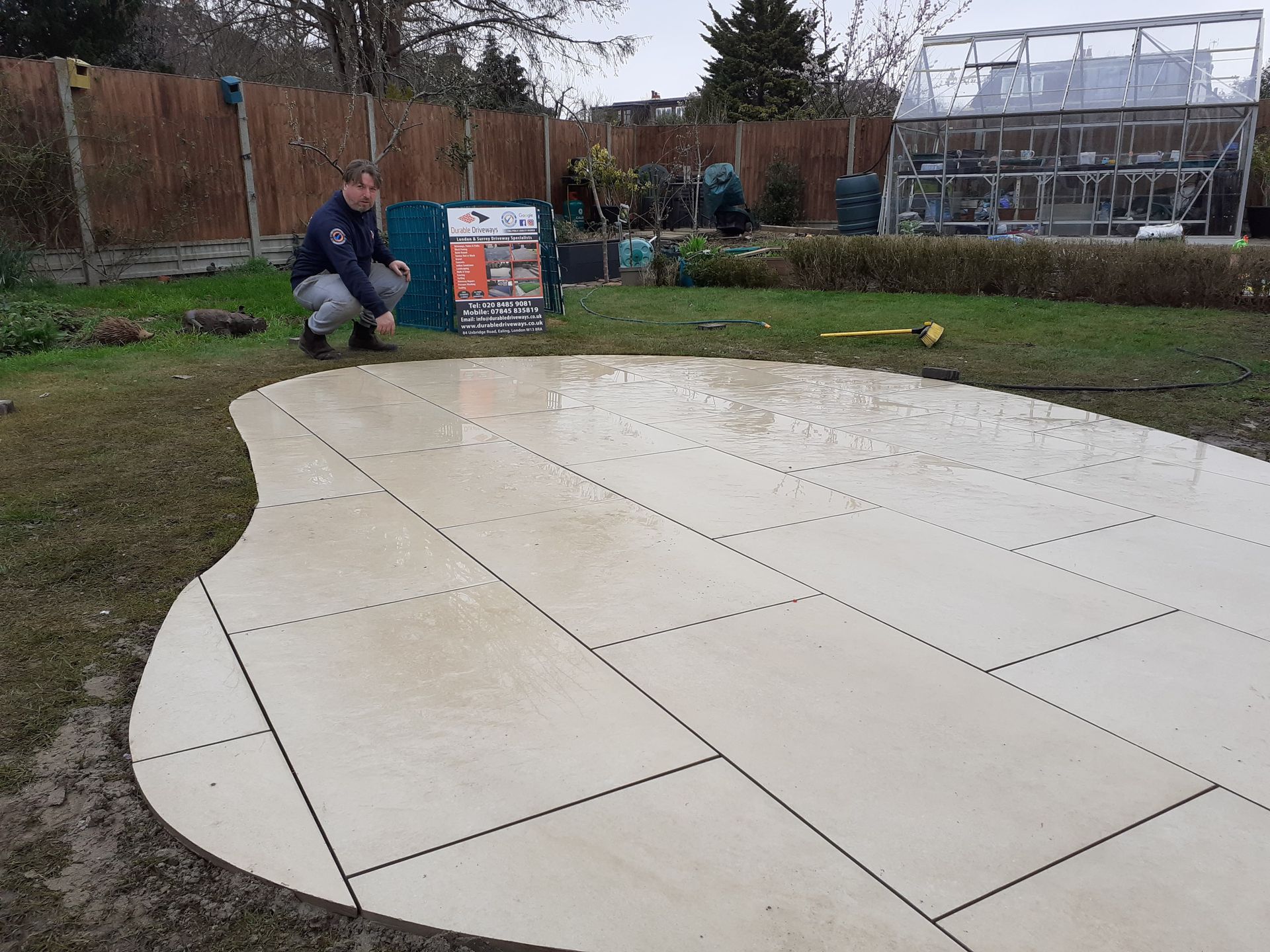 Two-story brick house with white gravel driveway, gray garage doors, and a blue sky.