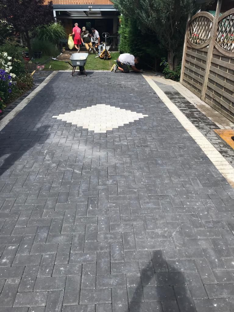 Paved driveway with a diamond design, featuring workers in the background.
