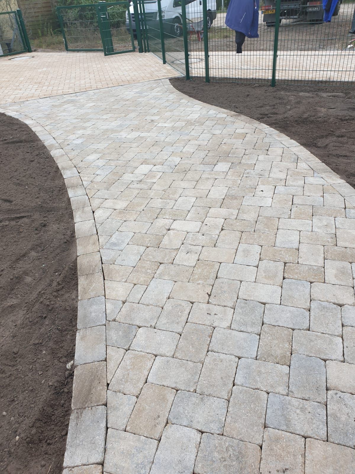 Curving brick paver pathway through a park-like setting.