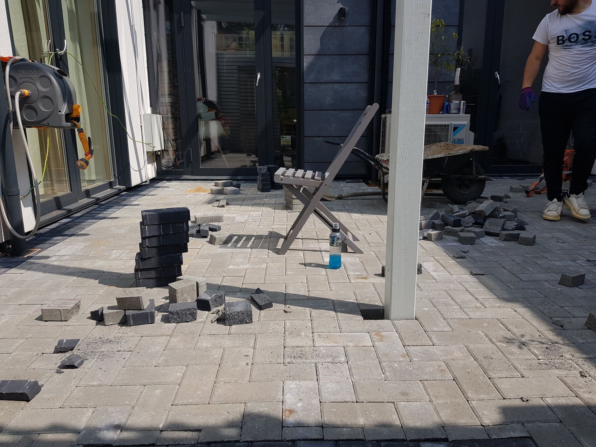 Patio under construction; paving stones scattered. A person in the background.