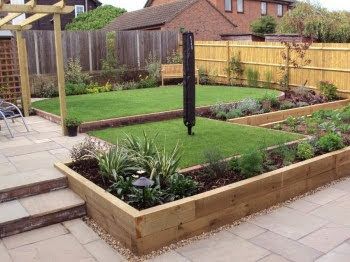 Stone patio leading toward a manicured lawn with hedges and bushes.