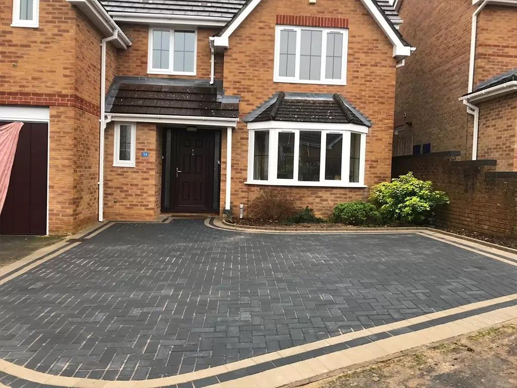 Stone patio leading toward a manicured lawn with hedges and bushes.