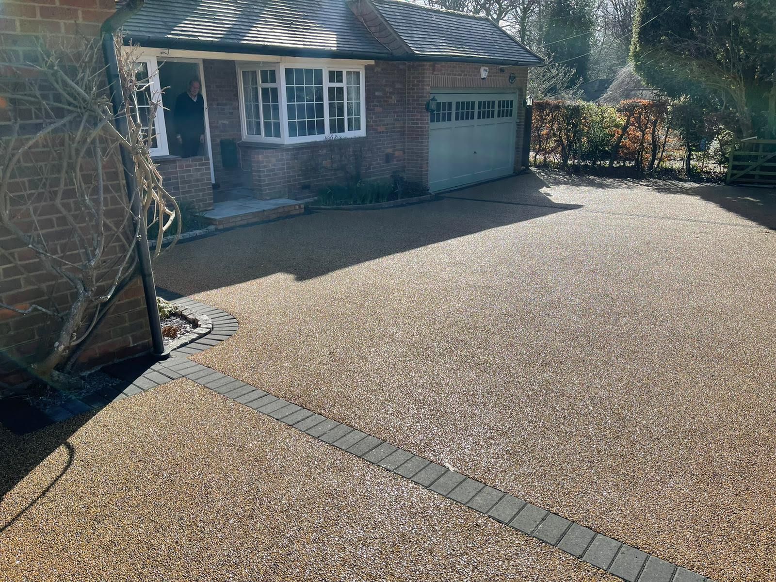 Resin driveway in front of a brick house with a garage.