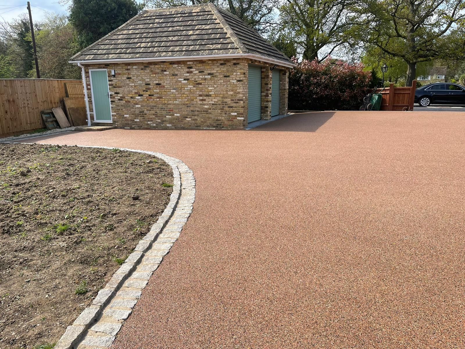 Gravel driveway with stone-built garage, bordered by a garden bed.