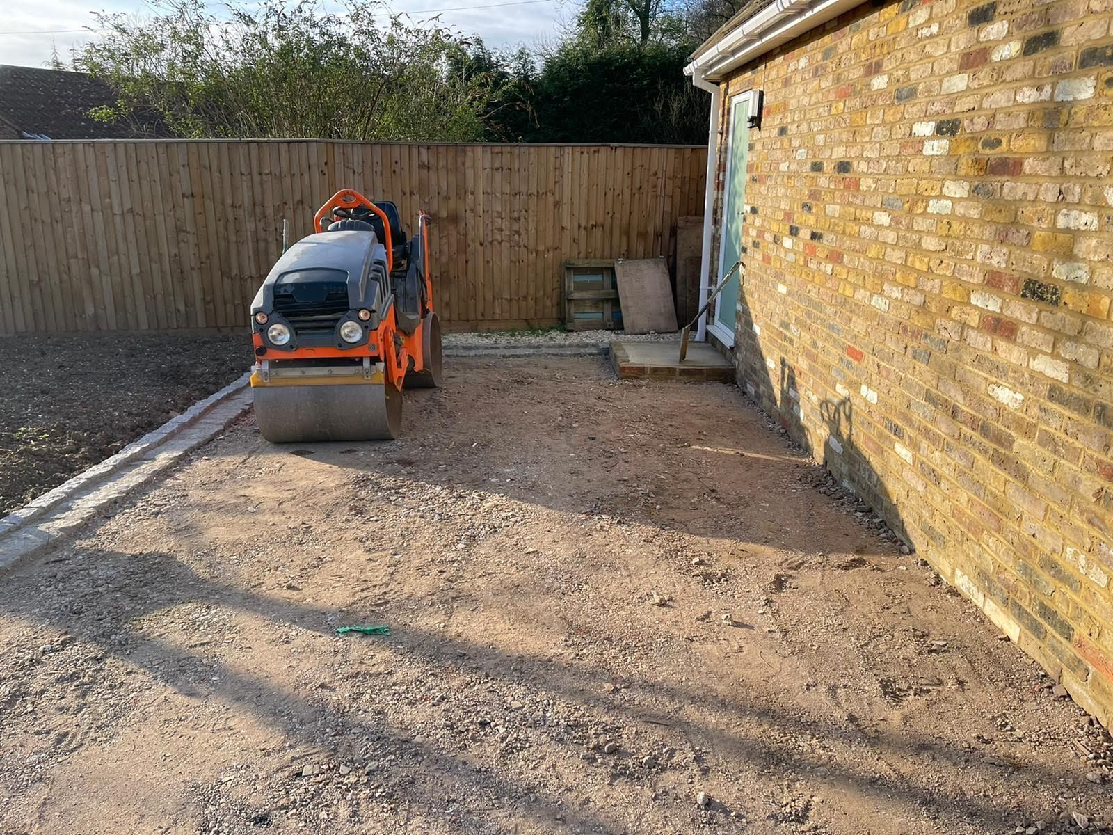 Patio under construction; paving stones scattered. A person in the background.