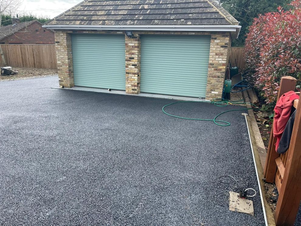 Dark gravel driveway in front of a garage with two light blue roller doors.