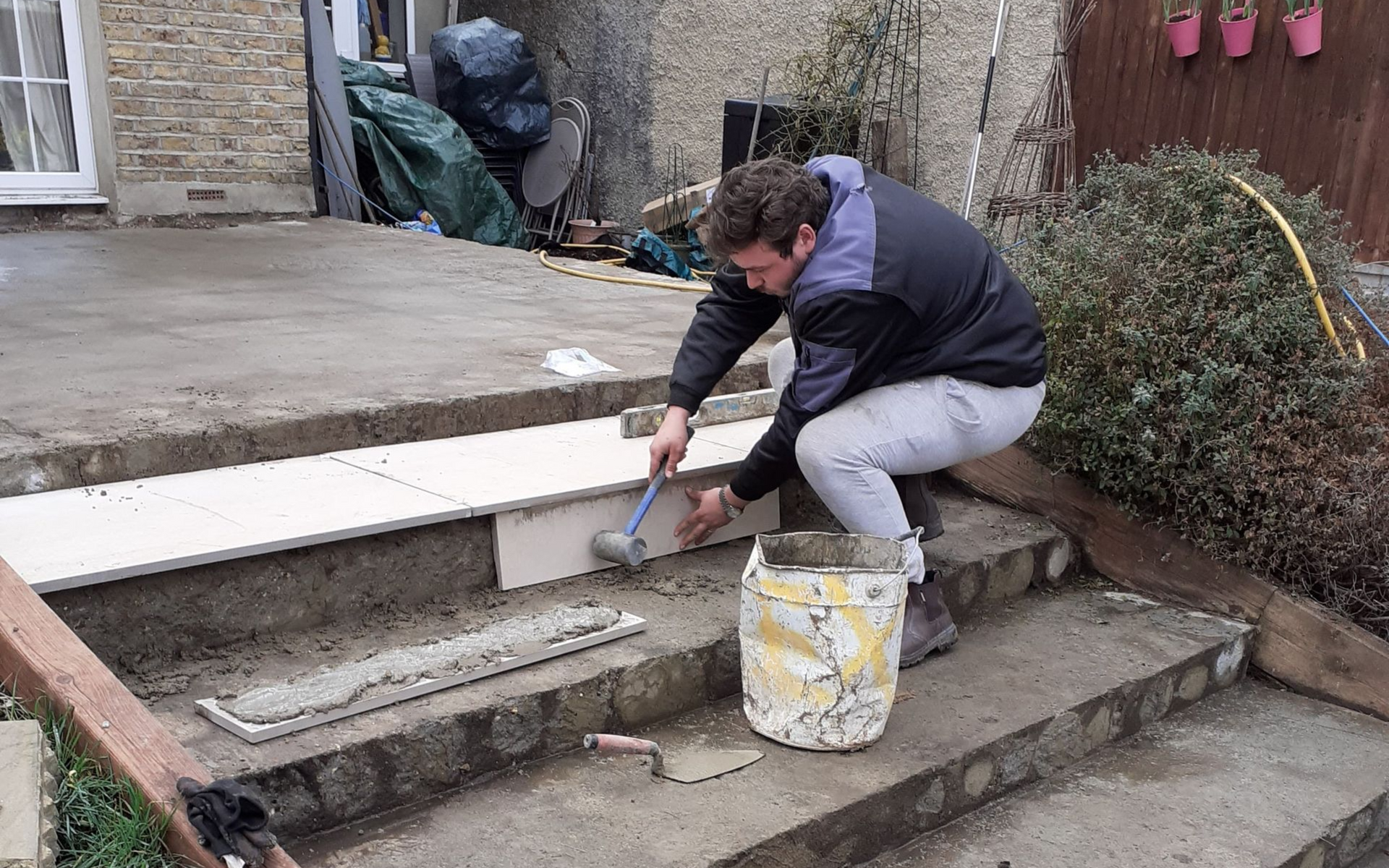 Patio under construction; paving stones scattered. A person in the background.