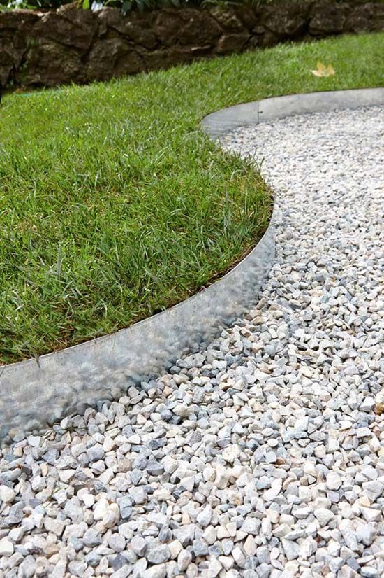 Gray gravel path curving next to green grass, separated by a concrete border.
