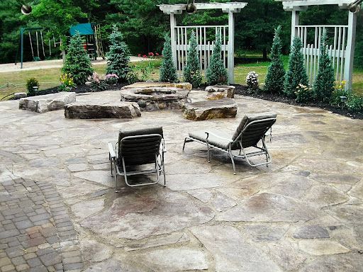 Patio with lounge chairs, fire pit, and landscaping, near a playground.