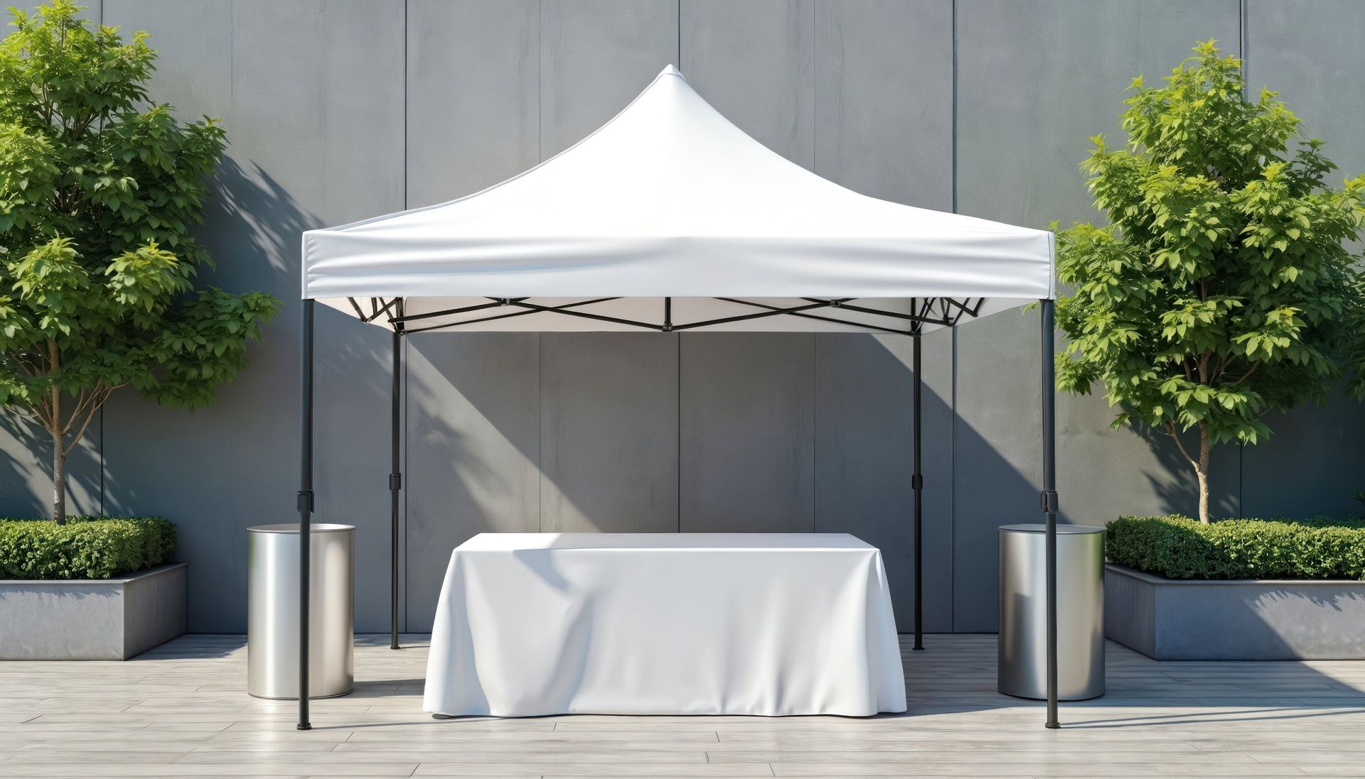 White canopy tent with a covered table set up outdoors between two potted trees.