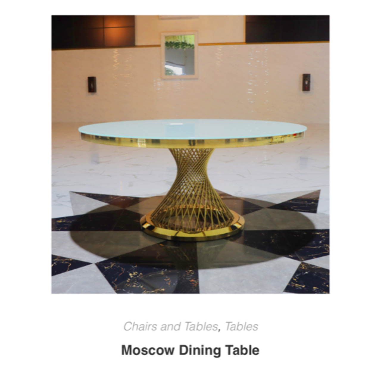 Modern round glass dining table with a gold sculptural base on a black-and-white tiled floor