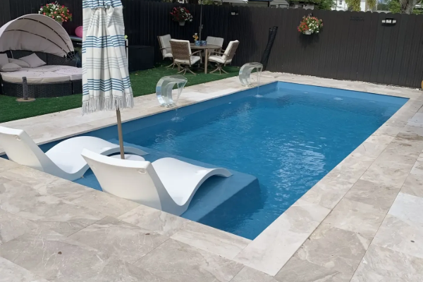 Backyard pool with blue water, white lounge chairs, and a patio umbrella