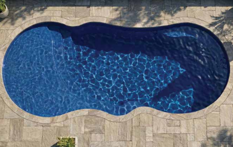 Overhead view of a blue, kidney-shaped swimming pool surrounded by stone paving