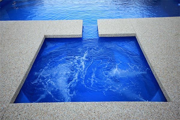 Blue water feature bordered by gray stone, with a central cutout pool and rippling water surface