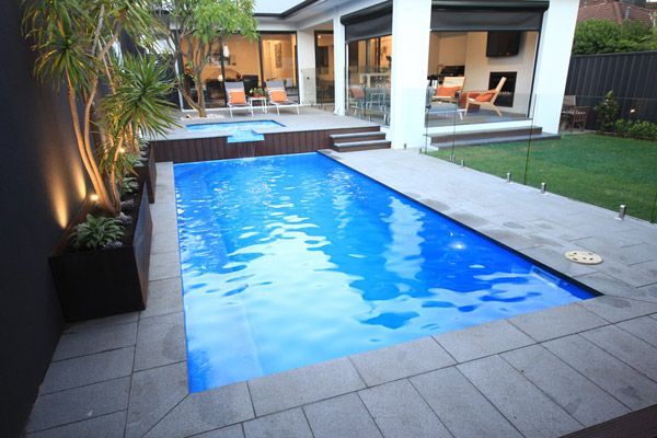 Modern backyard patio with a rectangular blue swimming pool and lounge area
