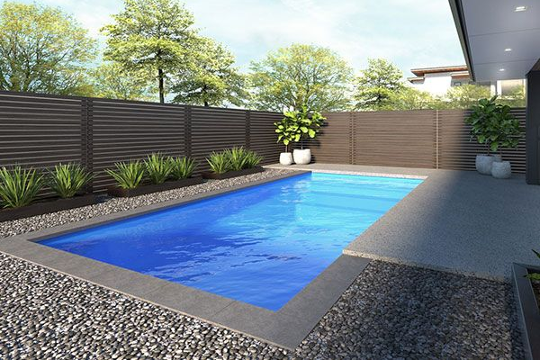 Modern backyard with a rectangular blue swimming pool, gray patio, and wooden privacy fence.