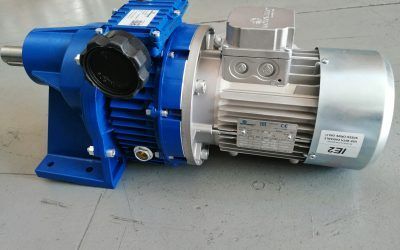 Motore industriale blu e argento con cambio su una superficie grigia.