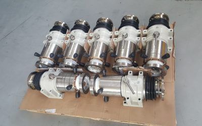 Sei meccanismi industriali simili a pompe su un foglio di cartone, con componenti argentati, neri e bianchi.