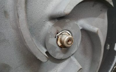 Primo piano di una parte in metallo grigio con un componente centrale cilindrico che mostra segni di usura.