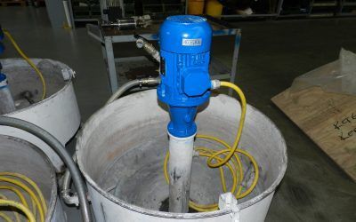 Motore elettrico blu collegato a un lungo tubo all'interno di un contenitore metallico bianco. Cavo elettrico giallo presente.