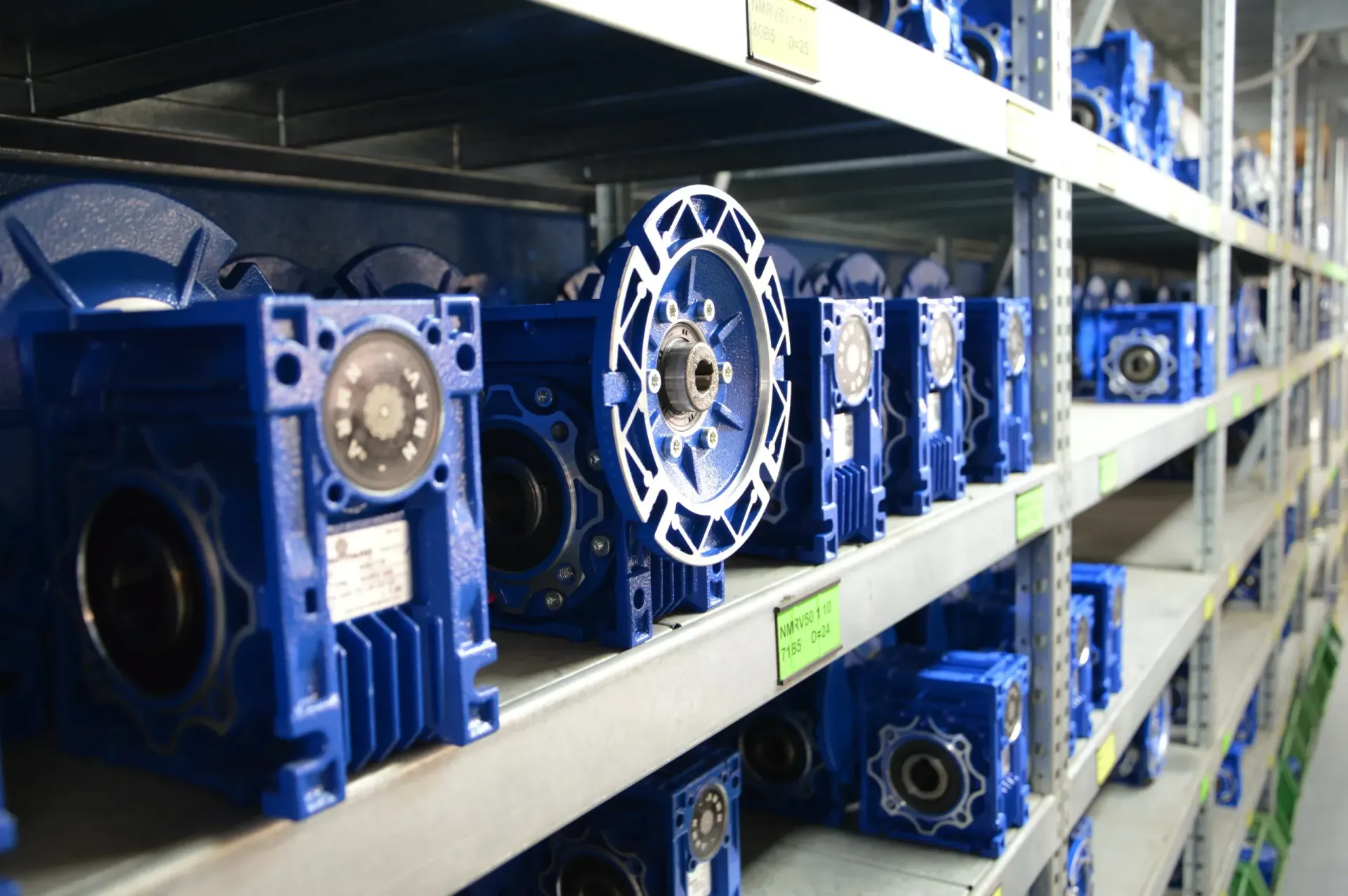 Riduttori industriali blu su scaffalature metalliche in un magazzino.