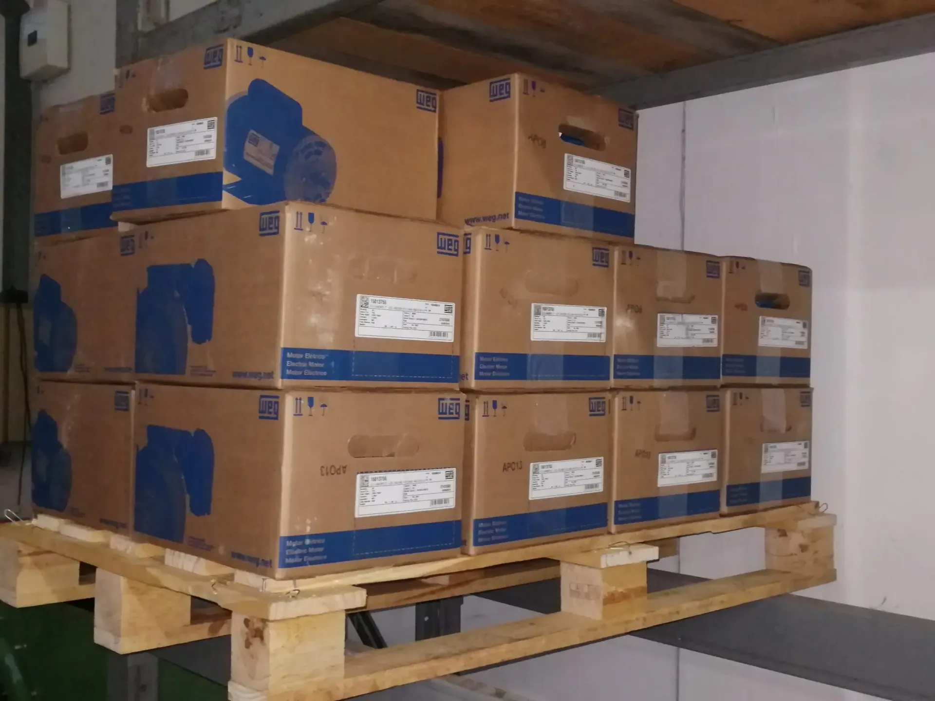 Scatoloni di attrezzature impilati su un pallet di legno in un'area di stoccaggio.