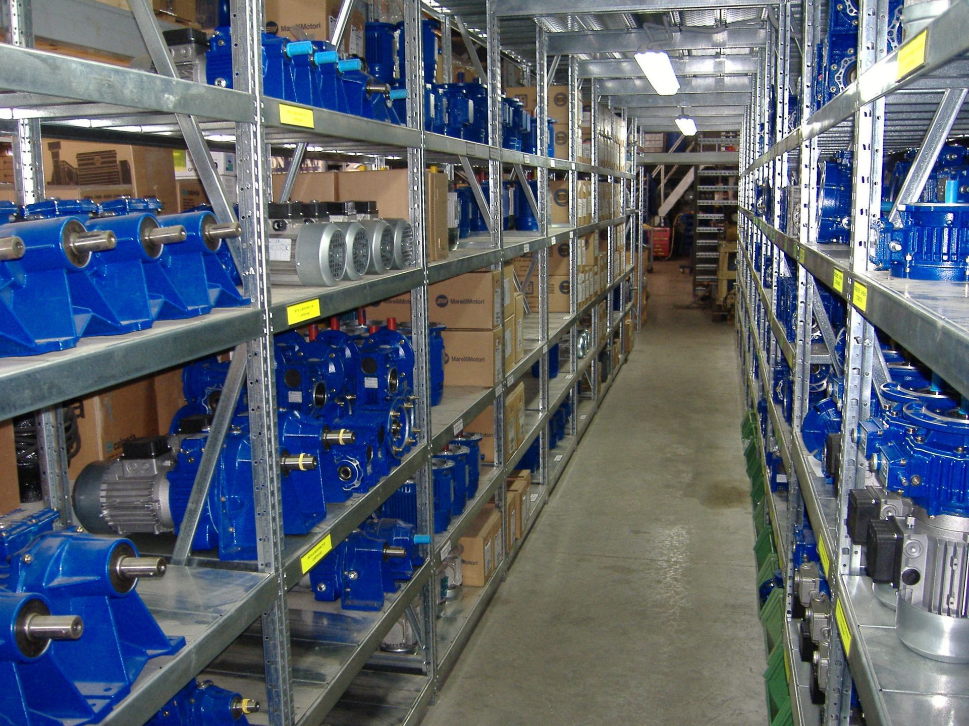 Magazzino con file di scaffali contenenti attrezzature industriali blu.