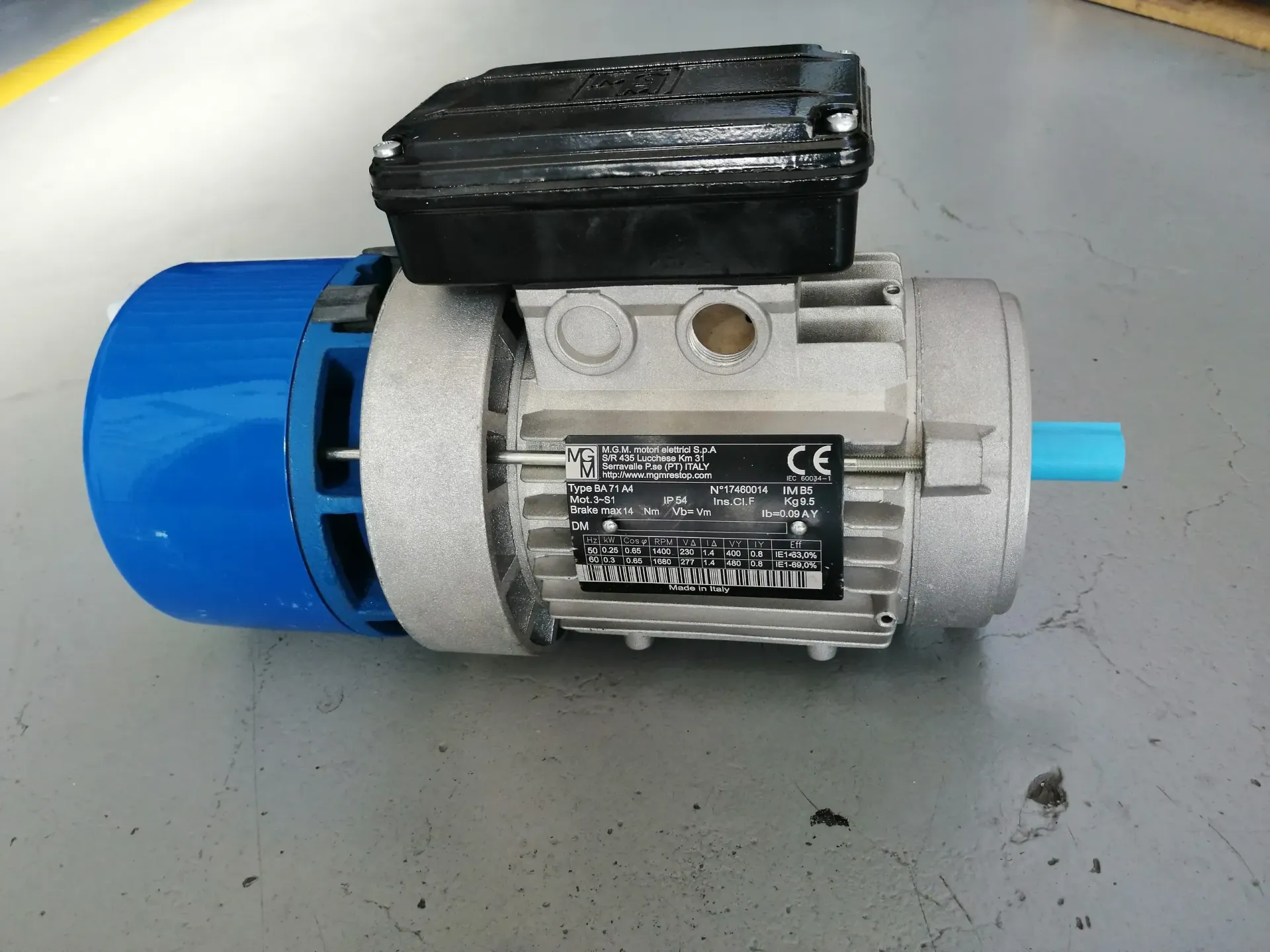 Motore elettrico con tappo terminale blu, corpo grigio, parte superiore nera e albero azzurro.