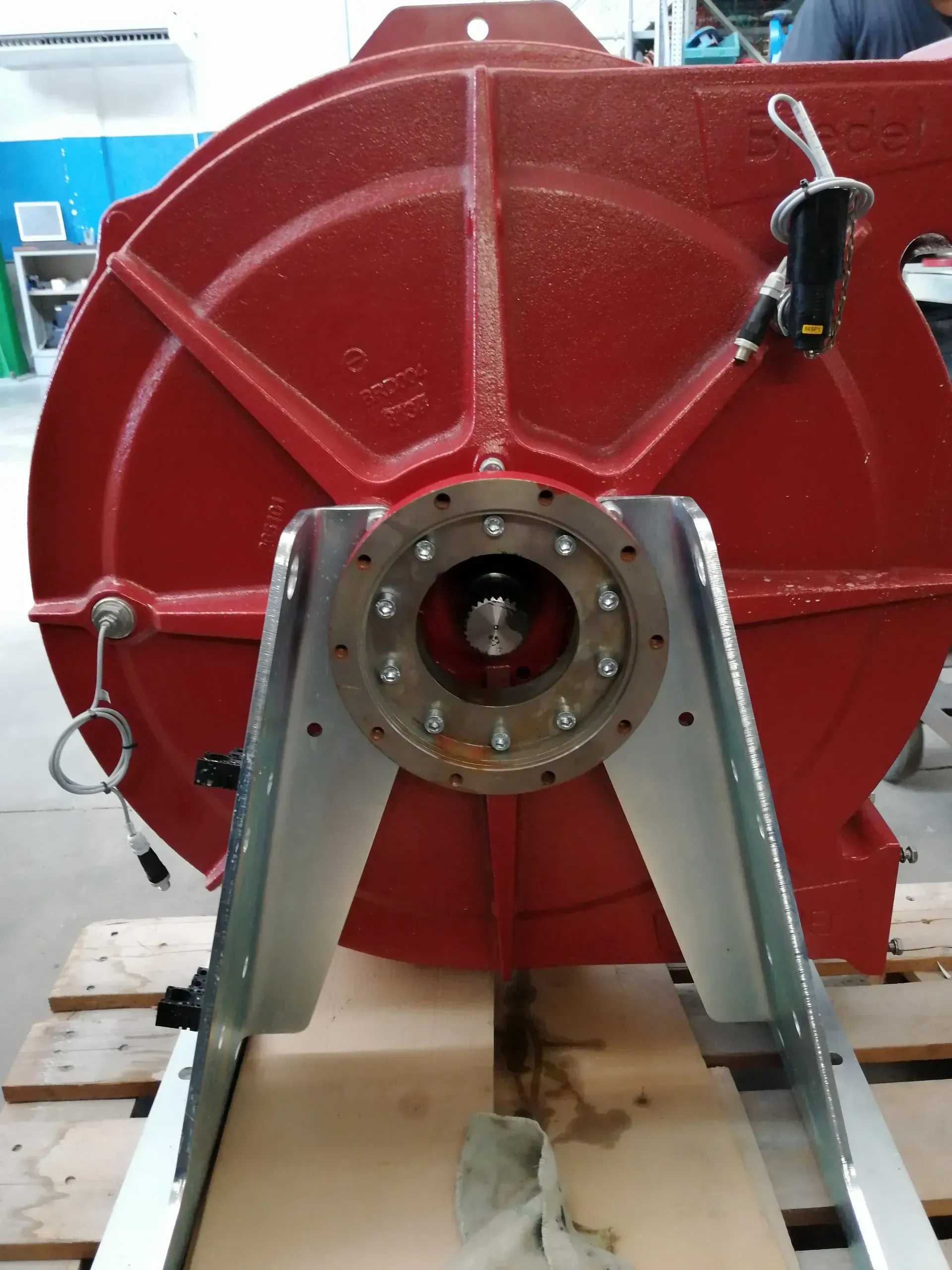 Macchina industriale rossa montata su un supporto metallico argentato; il suo albero è visibile.