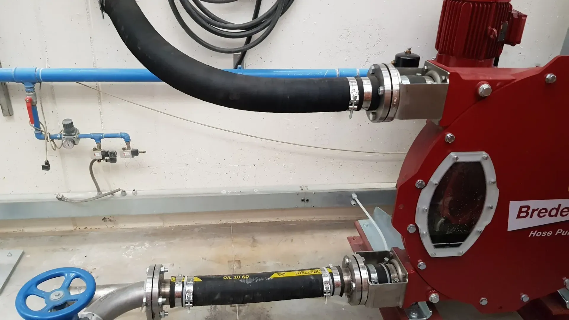 Pompa rossa con tubi neri collegati a tubi blu e metallici, all'interno.