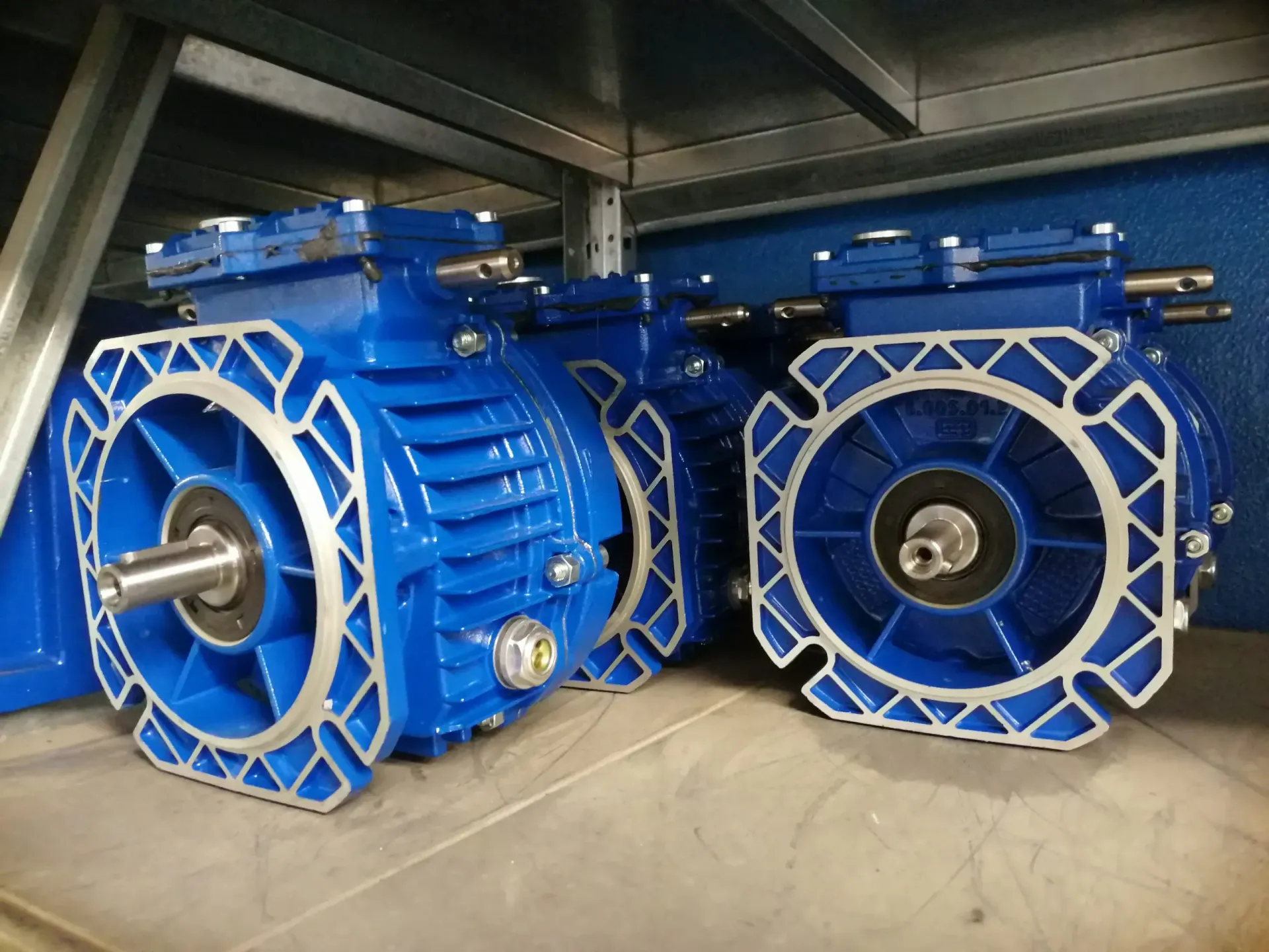 Motori elettrici industriali blu impilati su uno scaffale.