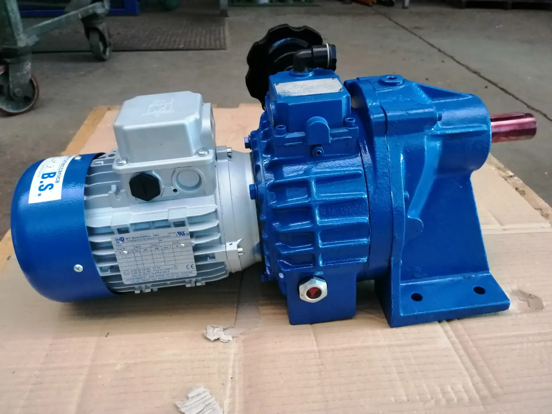 Motore elettrico blu accoppiato a un cambio blu, appoggiato su una superficie.