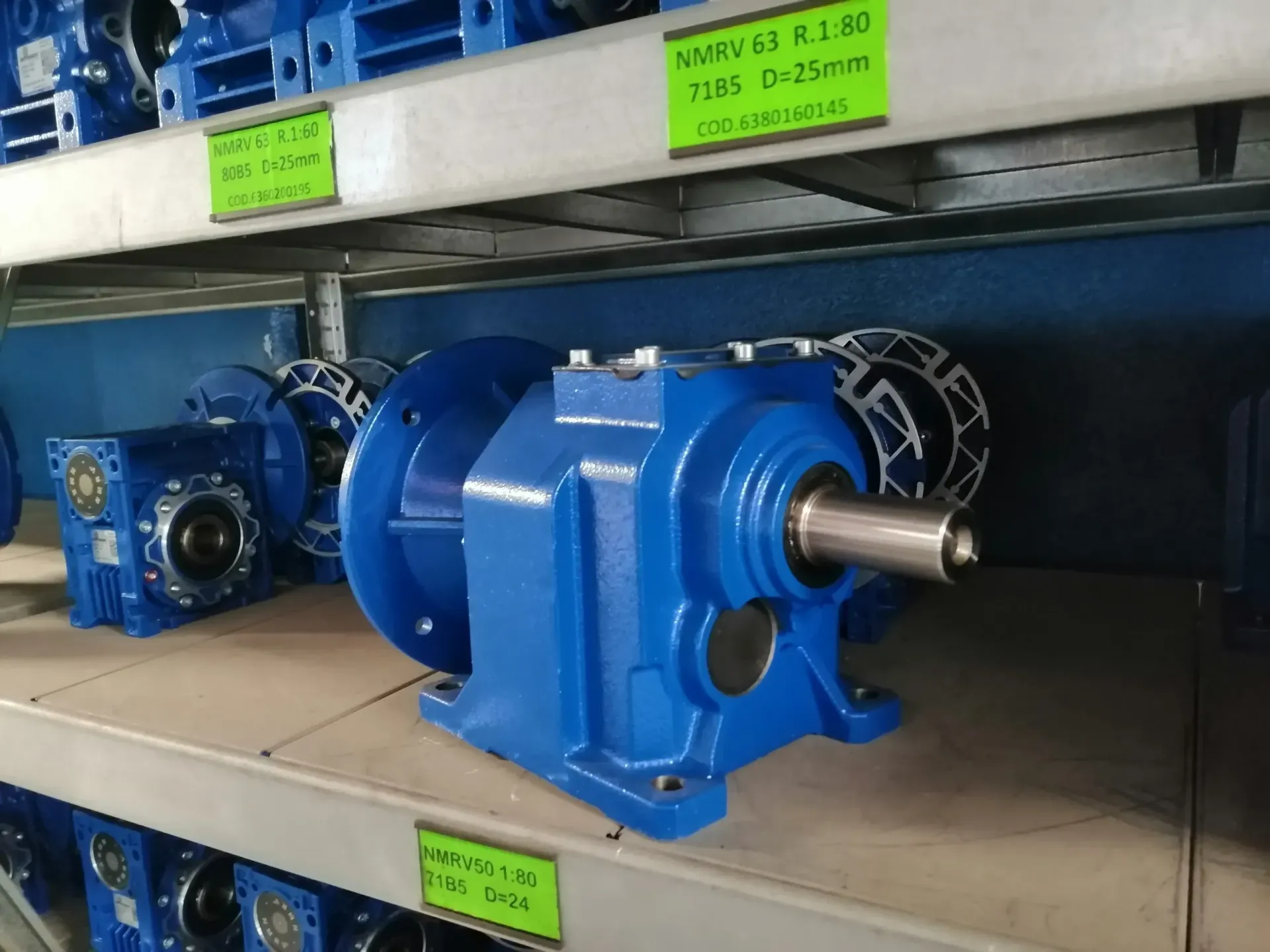 Scatola ingranaggi industriale blu su uno scaffale con etichetta prodotto verde.