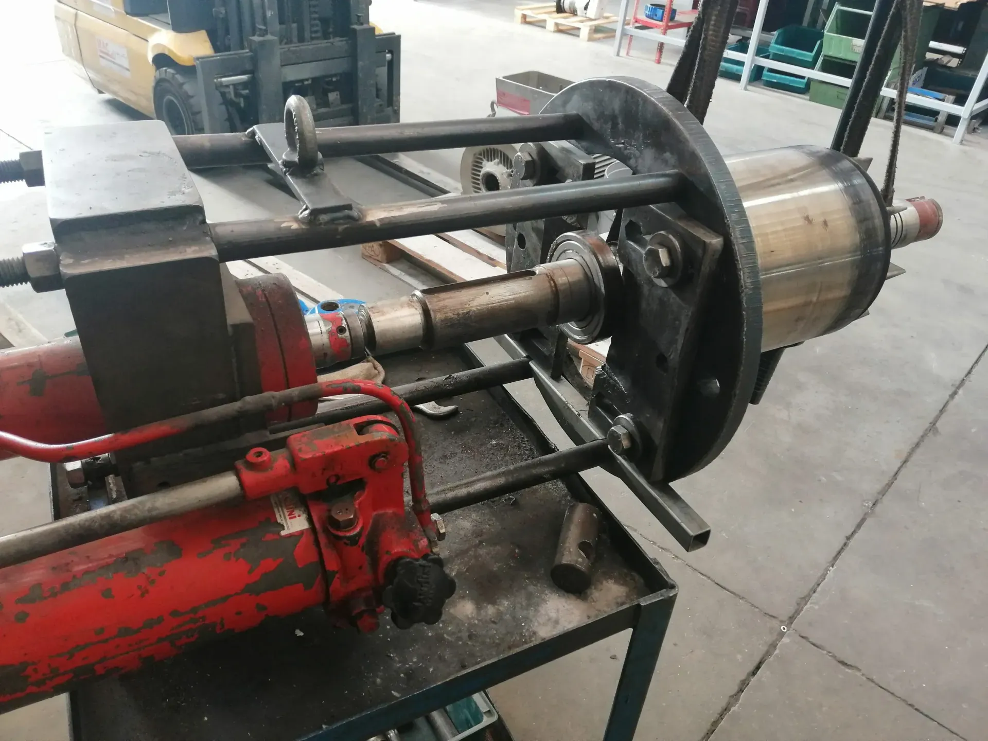 Una macchina idraulica rossa con una bobina di metallo per avvolgere il cavo in un'officina.