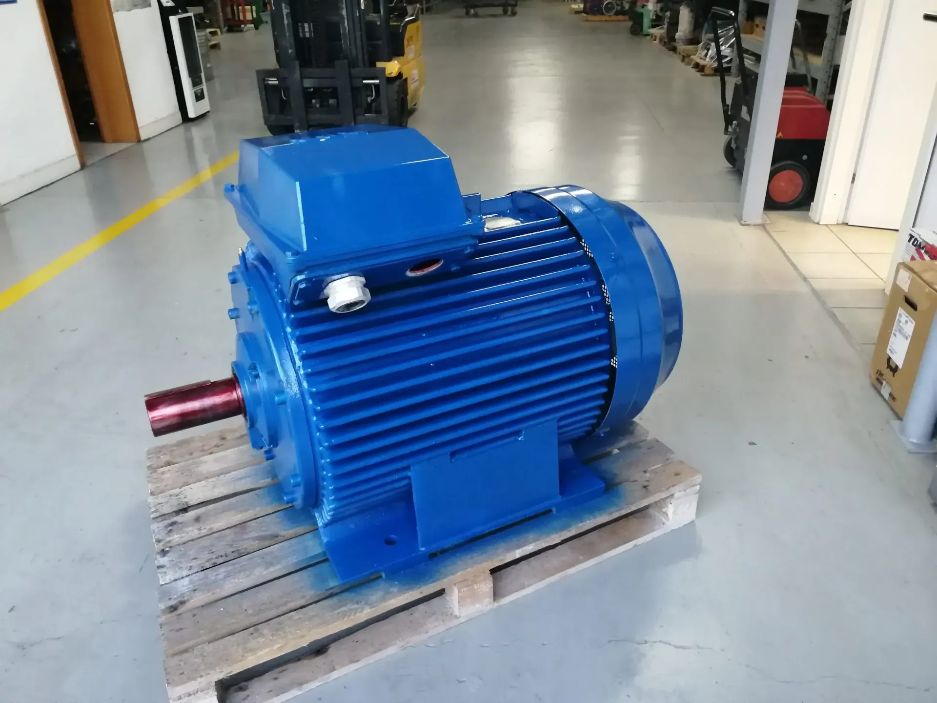 Motore elettrico blu su un pallet di legno in un magazzino.