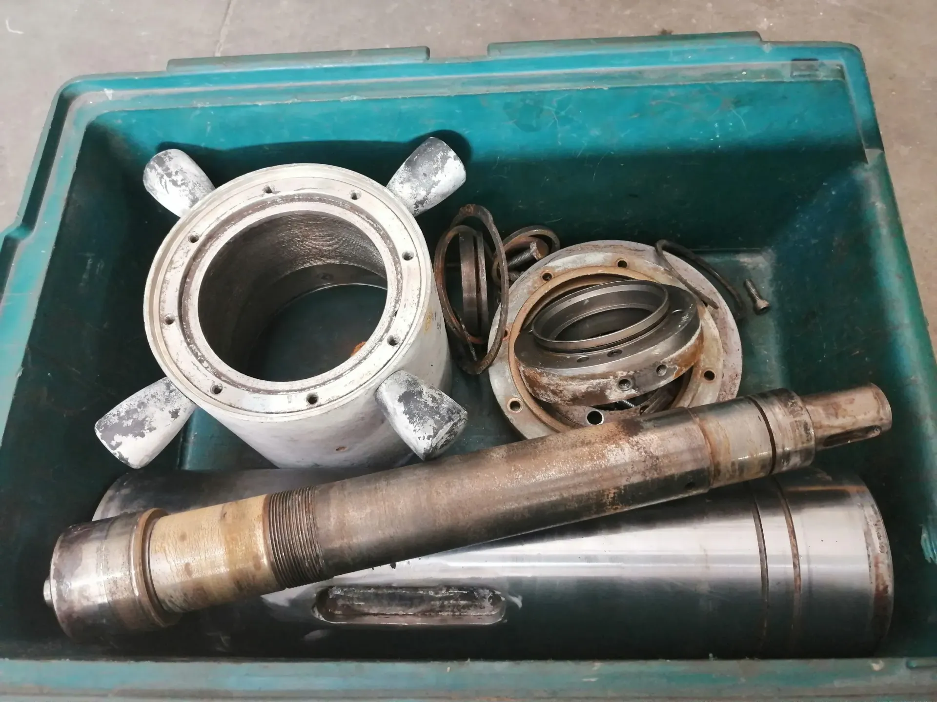 Parti metalliche di macchinari all'interno di una cassetta degli attrezzi verde.