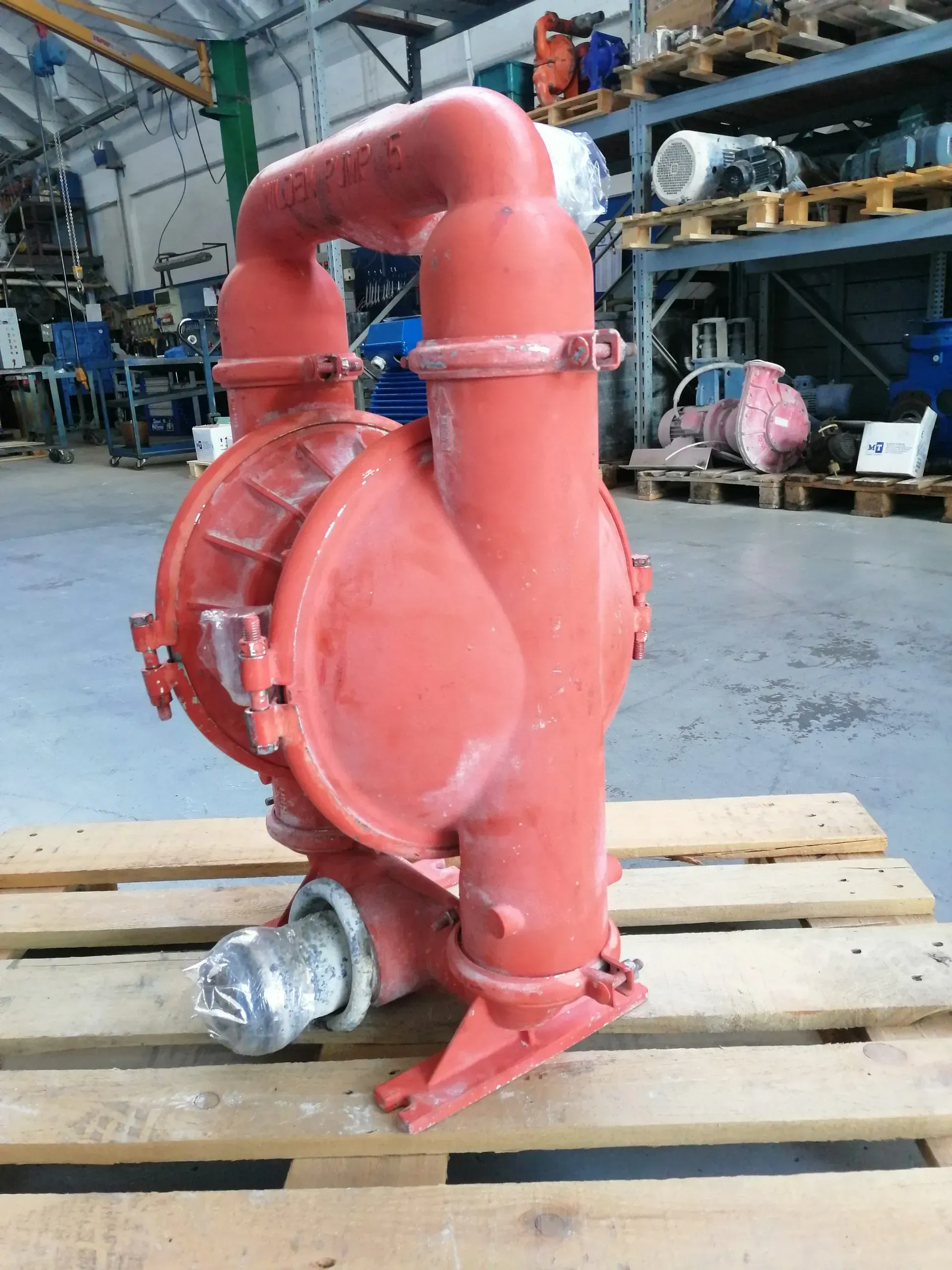 Pompa industriale rossa su un pallet di legno in un magazzino.