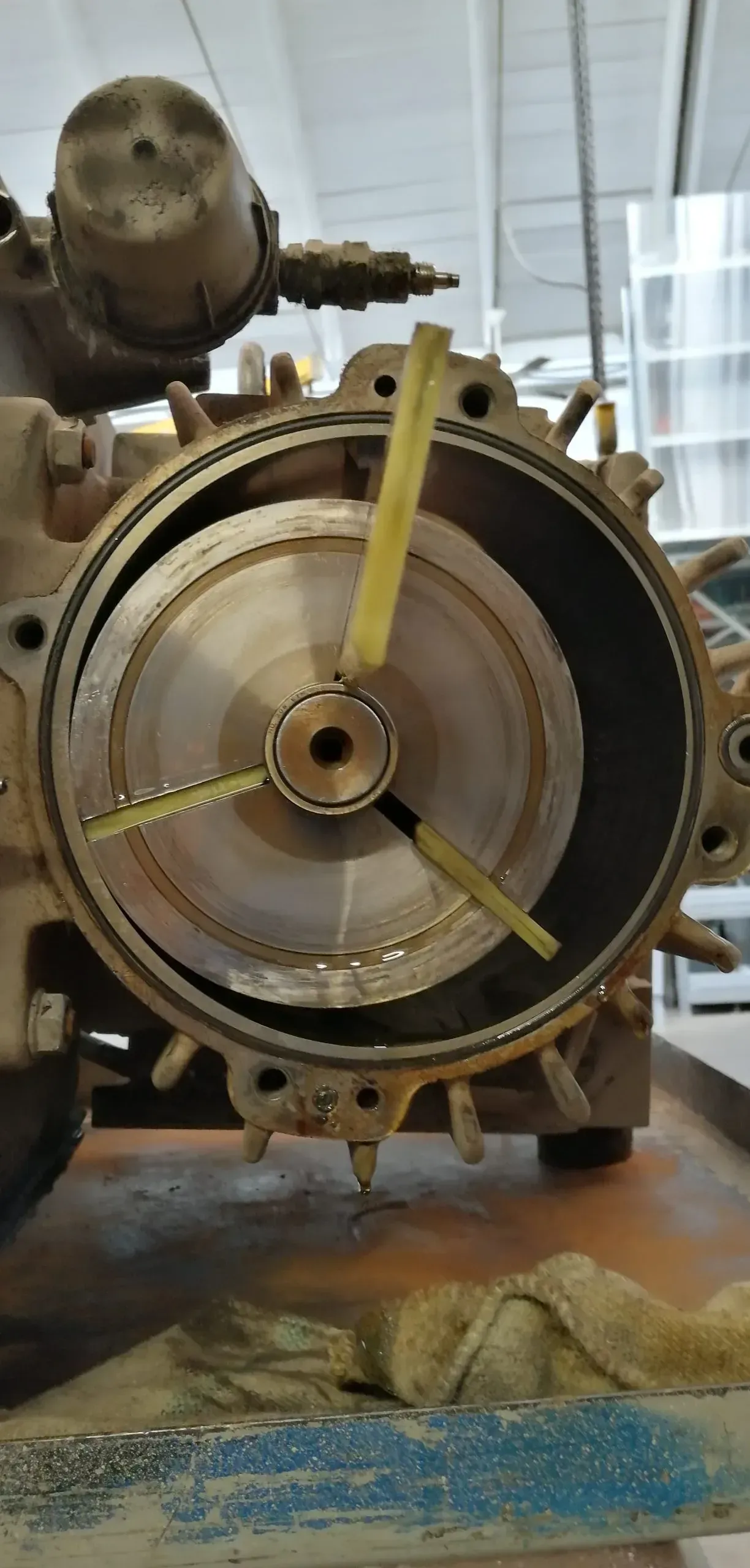 Primo piano dell'interno di una macchina con un componente circolare e tre lame gialle; è visibile un metro a nastro.