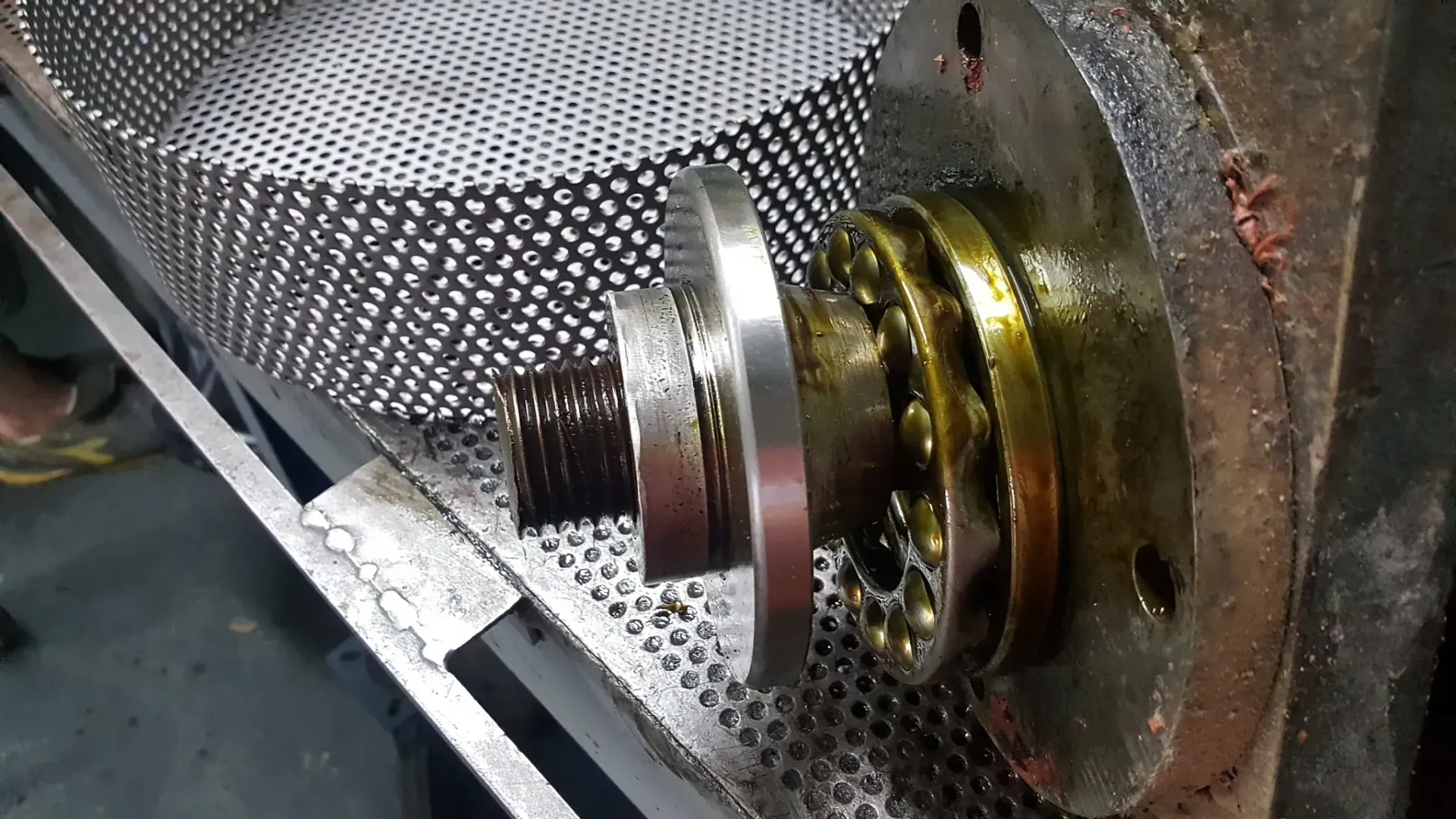 Parti meccaniche con struttura metallica circolare forata. Albero e cuscinetti ricoperti d'olio.