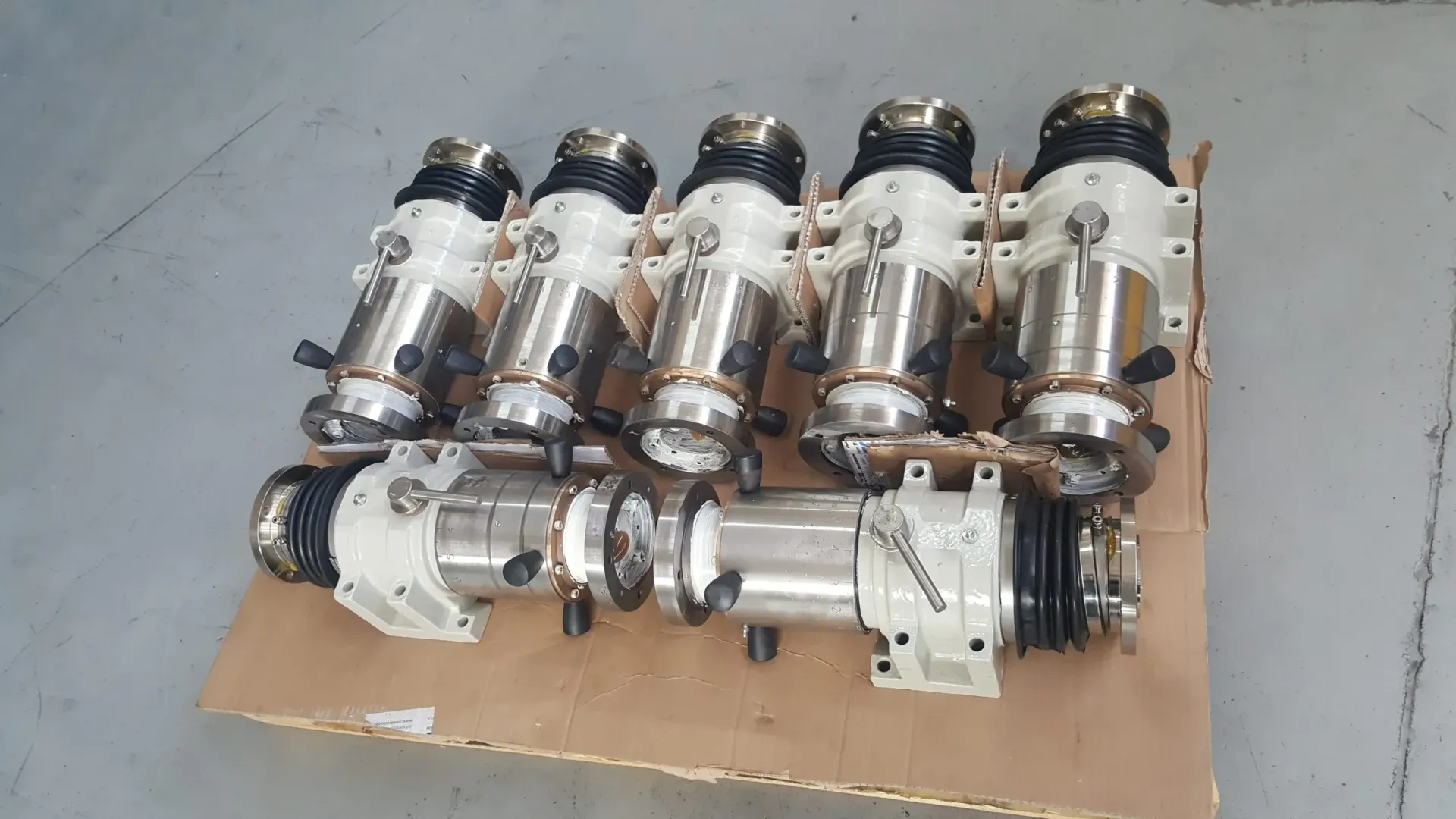 Fila di cinque meccanismi industriali metallici e beige su cartone.