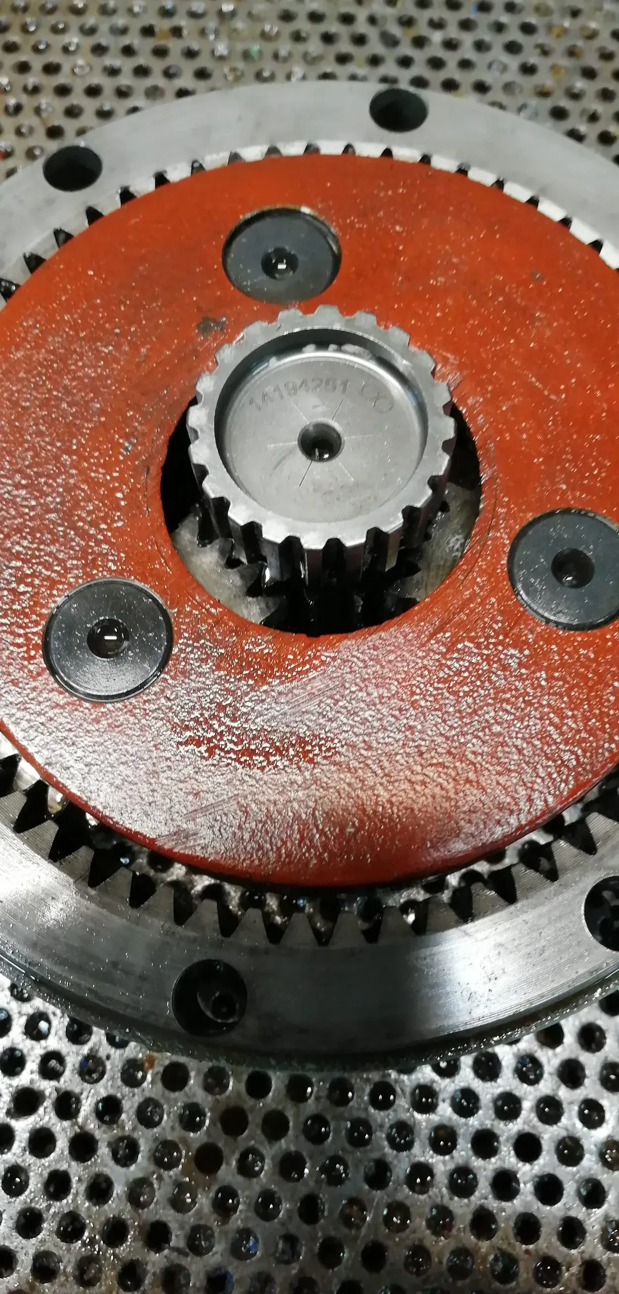 Primo piano del sistema di ingranaggi di una macchina. Al centro c'è un pezzo circolare rosso con un ingranaggio più piccolo. Altri ingranaggi lo circondano.