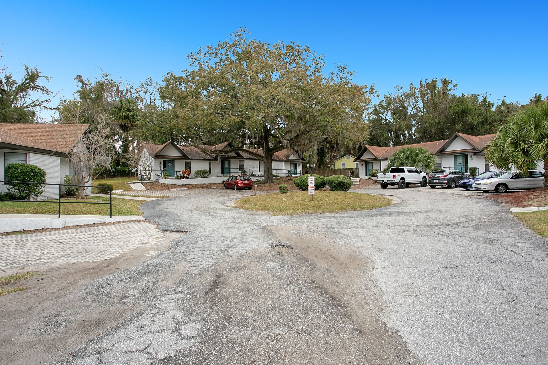 A row of apartments with cars parked on the side of the road.
