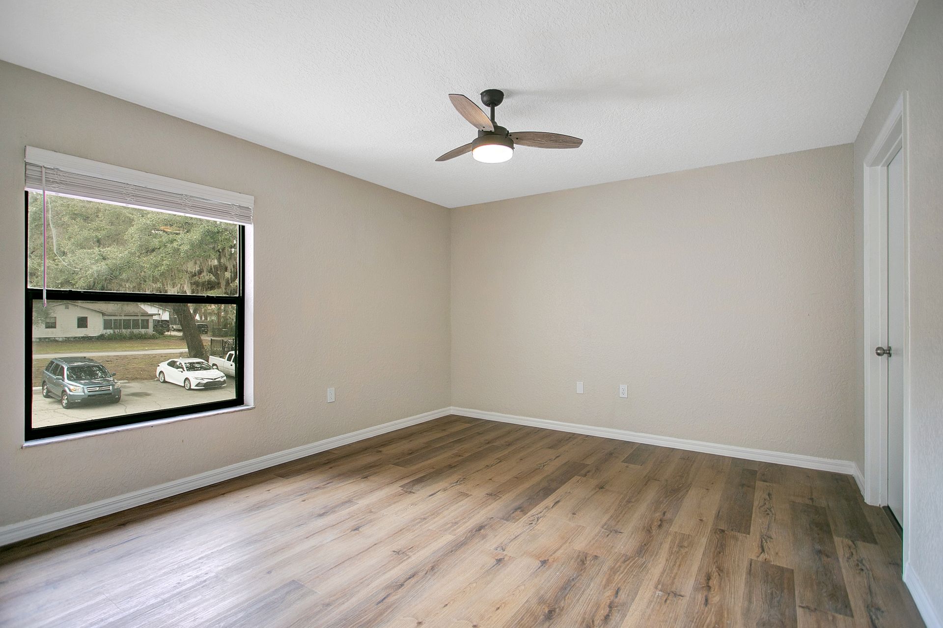 An empty room with hardwood floors and a ceiling fan.