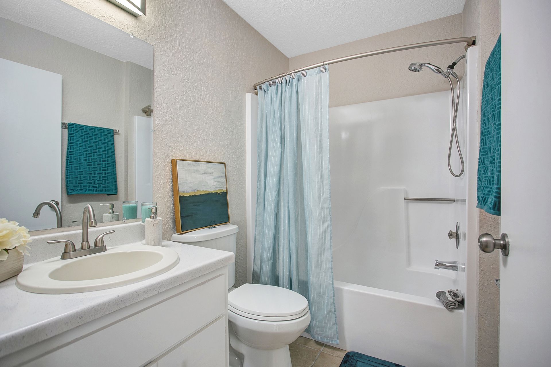 A bathroom with a toilet, sink, bathtub and shower curtain.