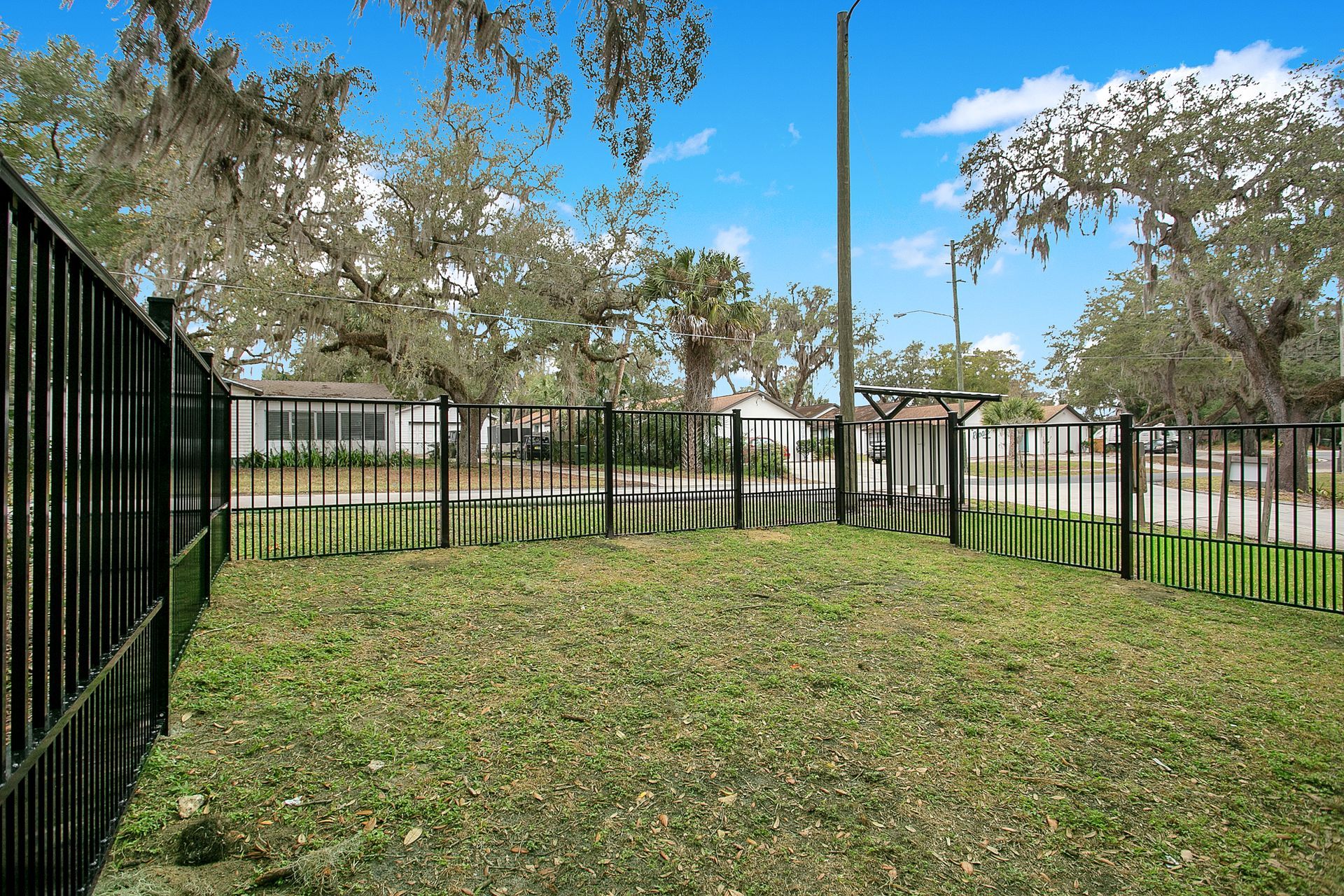 A fence surrounds a grassy field with trees in the background.