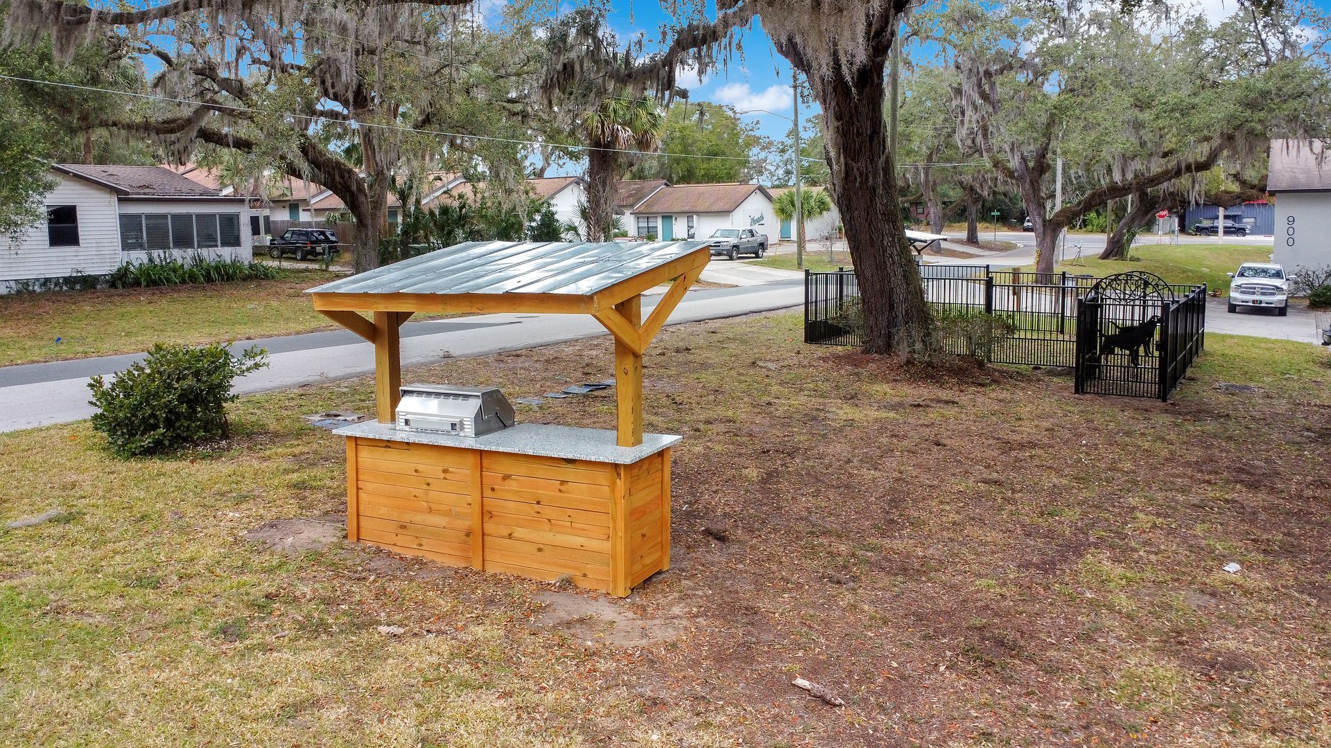 A wooden gazebo with a grill on top of it in a yard.