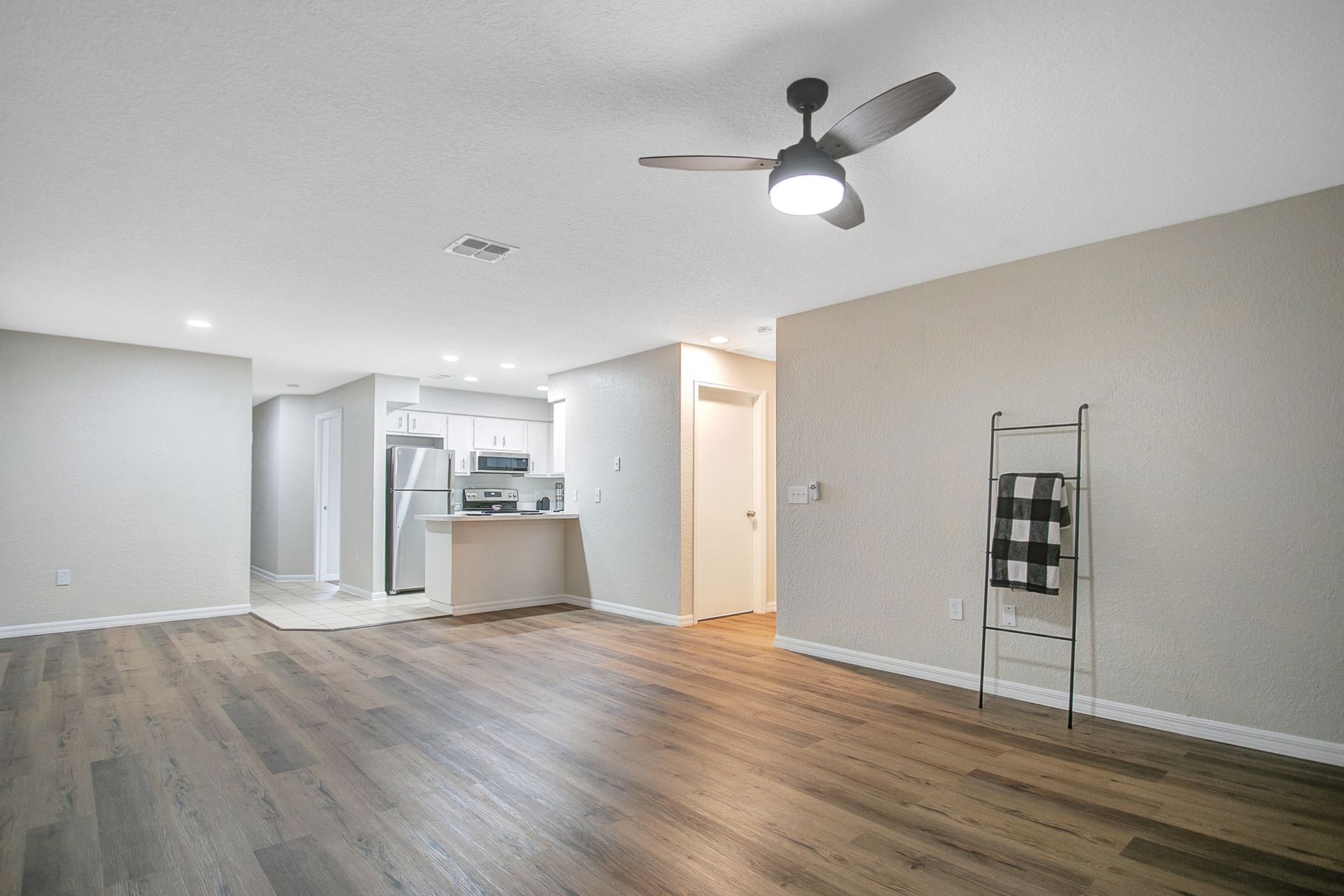 A living room with hardwood floors and a ceiling fan.