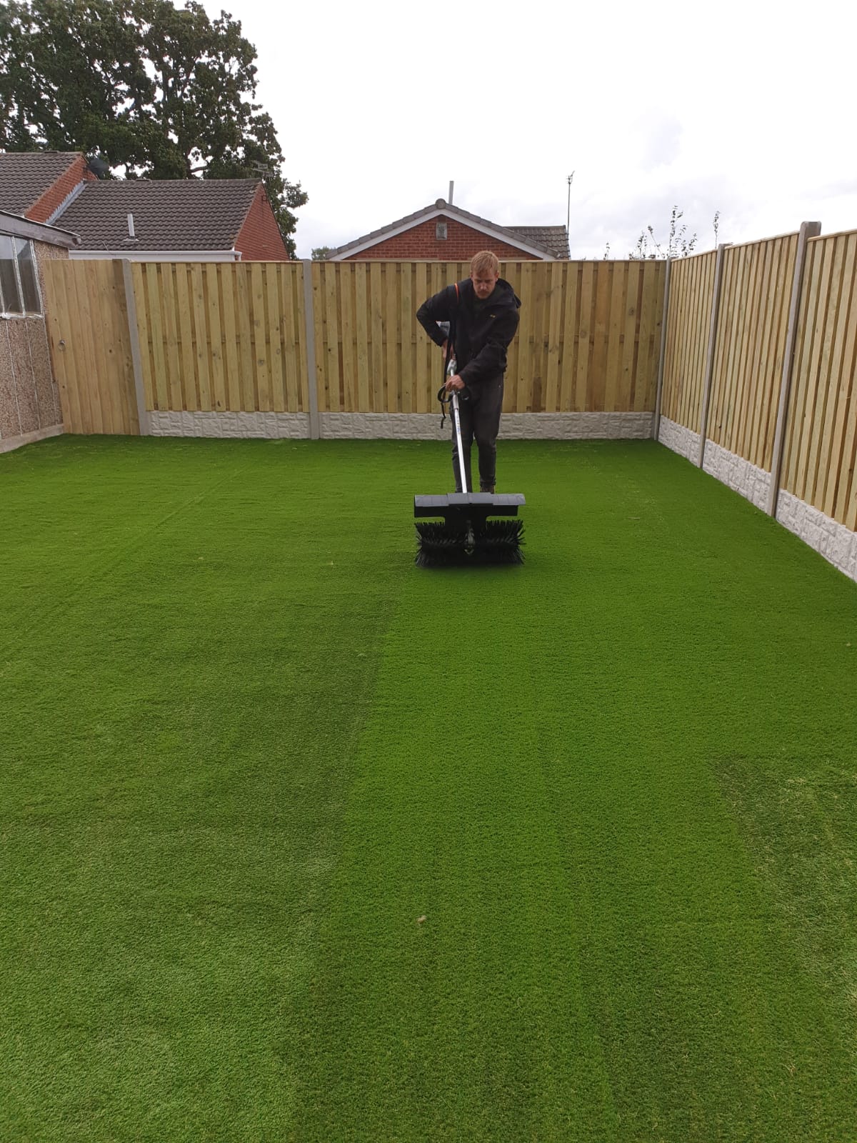 Final brushing of artificial grass lawn to stand up the blades on project in Handsworth Sheffield