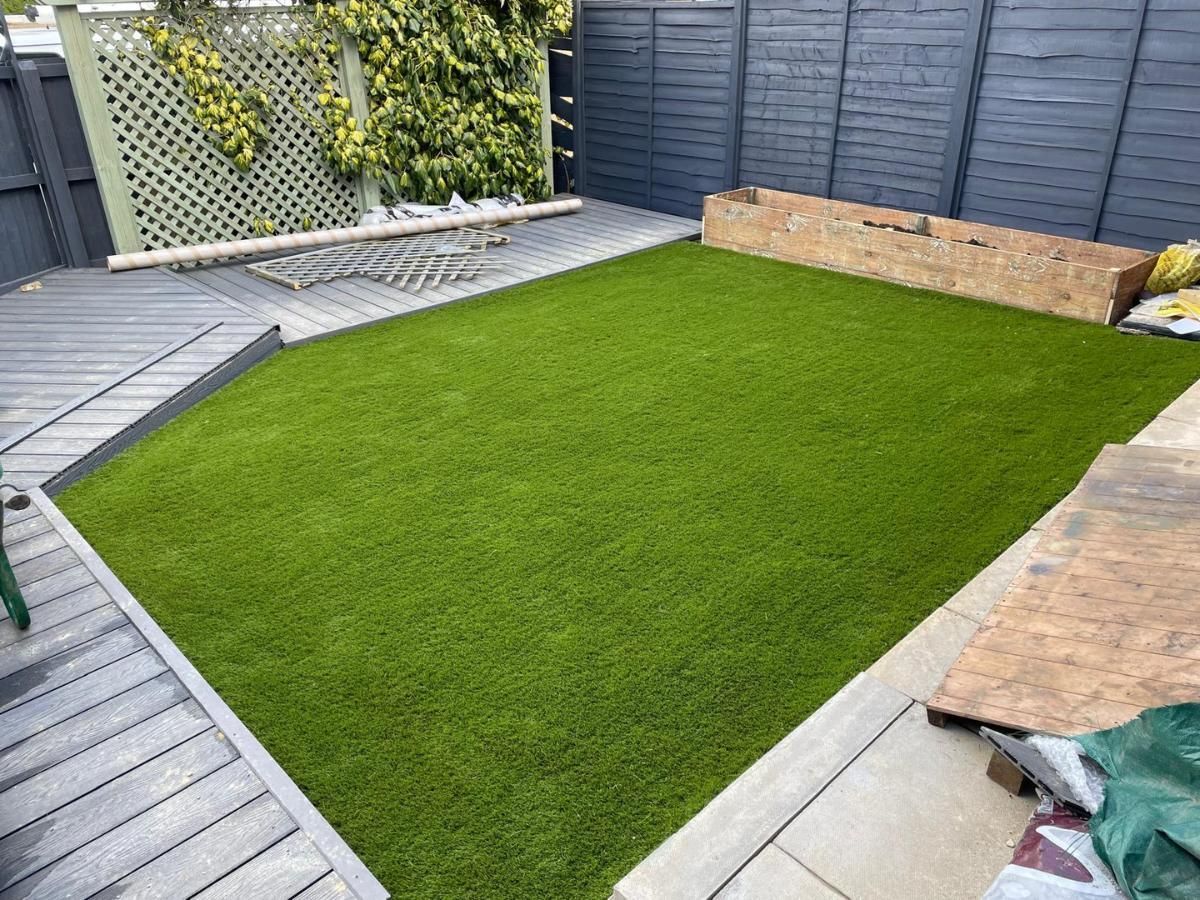 Zest Artificial Grass Oakham fake lawn fitted along a raised flower bed and decking surround
