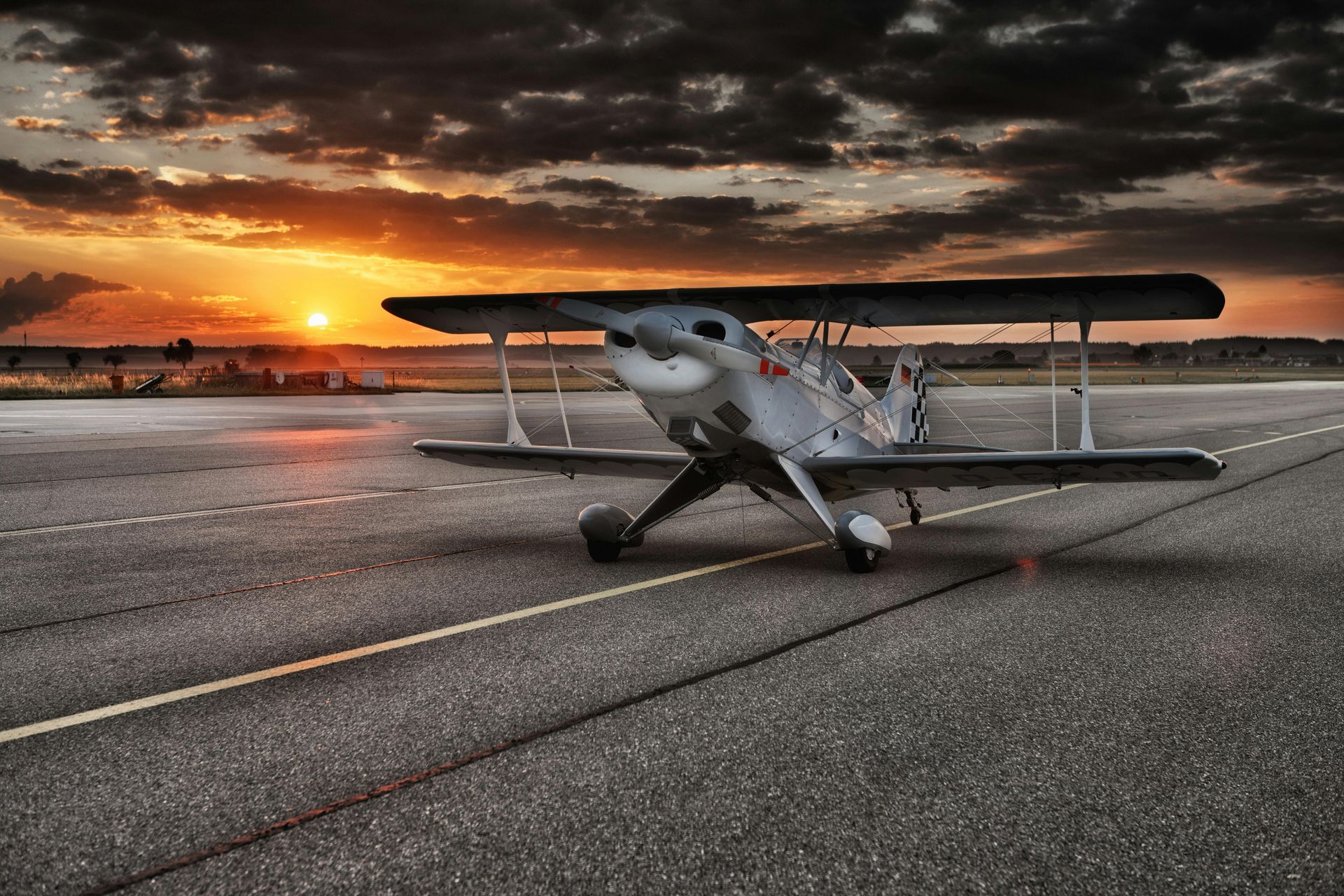 A small plane is parked on a runway at sunset